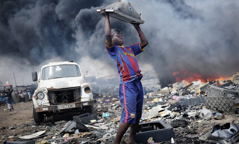 Agbobloshie, Ghana; a young man carrying e-waste.. Picture: CREDIT: KAI LÖFFELBEIN